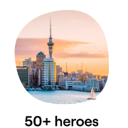 An image of the Auckland skyline featuring the Sky Tower with the waterfront and a sailboat in the foreground, set against a vibrant sunset